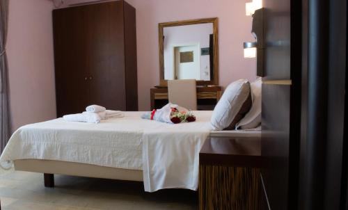 a bedroom with a bed with white sheets and a mirror at GOLDEN SUN Κokkoni Beach Hotel in Vrahati