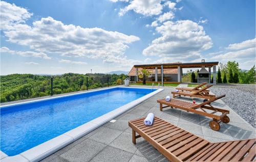 a swimming pool with two benches and a house at Amazing Home In Vinica Breg With Wifi in Gorušenjak
