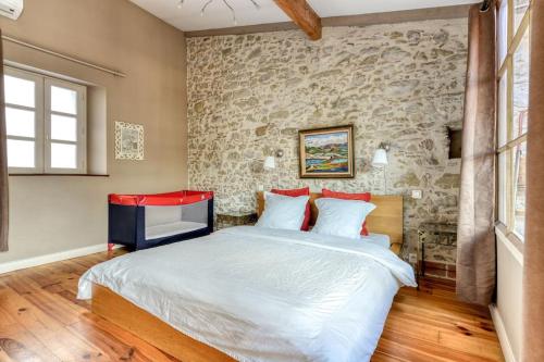 une chambre avec un grand lit et un mur en pierre dans l'établissement Loft centre-ville Parking, clim, wifi, à Carcassonne