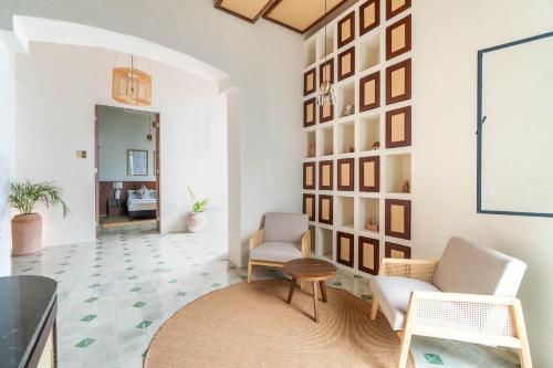a living room with two chairs and a wall with pictures at Hotel Boutique Santa Elena in Mérida