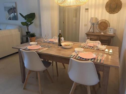 einen Esstisch mit weißen Stühlen und eine Flasche Wein in der Unterkunft Lovely apartment in Casares Beach in Casares