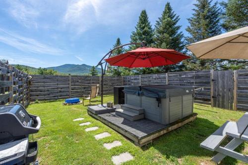 ein roter Sonnenschirm und ein Grill in einem Hof in der Unterkunft Heart of the White Mountains Cottage w Hot Tub #3 in Carroll
