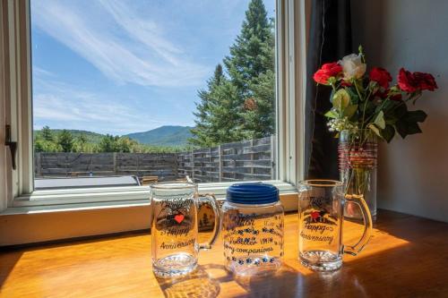 ein Tisch mit zwei Gläsern und einer Vase mit Blumen in der Unterkunft Heart of the White Mountains Cottage w Hot Tub #3 in Carroll