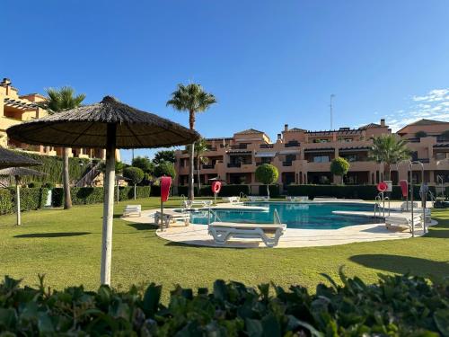 ein Swimmingpool mit Sonnenschirm und Stühlen und ein Resort in der Unterkunft Lovely apartment in Casares Beach in Casares