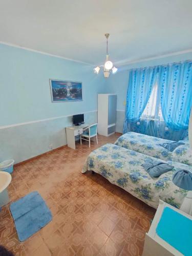 a bedroom with two beds and a desk and a window at Hotel Serenella in Turin