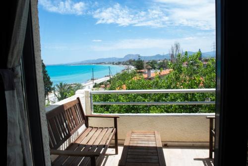 a balcony with two benches and a view of the ocean at GOLDEN SUN Κokkoni Beach Hotel in Vrahati