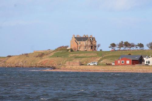 a large house on top of a hill next to the water at Caravan on Fantastic site in Dunbar