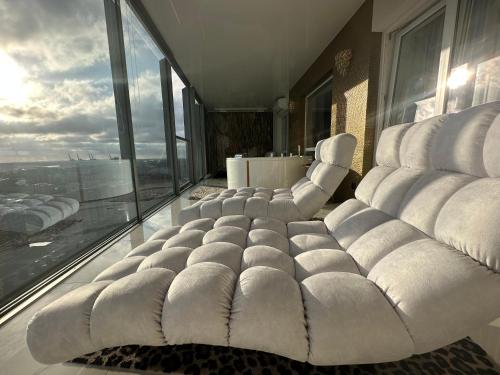 a large white couch in a room with windows at Premium Sky Jacuzzi Apartment in Klaipėda