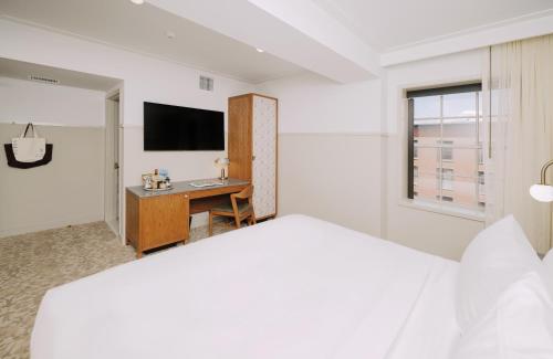a white bedroom with a bed and a desk at Hotel Heron Old Town Alexandria in Alexandria