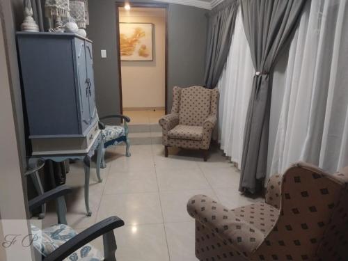 sala de estar con TV y 2 sillas en The Flamingo Suite at Frederick's Place, en Pretoria