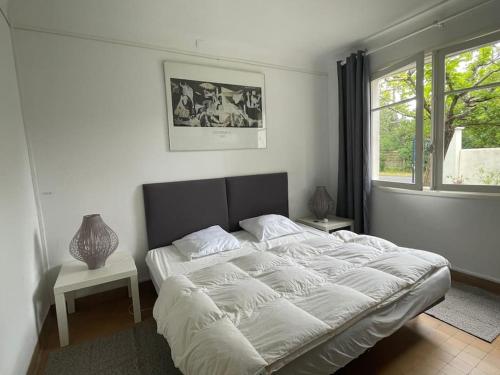 une chambre avec un grand lit blanc avec une fenêtre dans l'établissement LOUSTALOT2 Appartement en rez de jardin pour 6 personnes, à Soorts-Hossegor