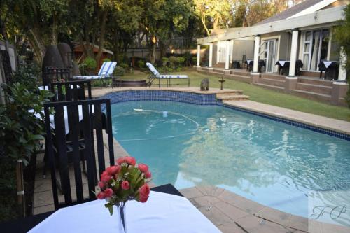 una piscina con un jarrón de flores sobre una mesa en The Flamingo Suite at Frederick's Place, en Pretoria