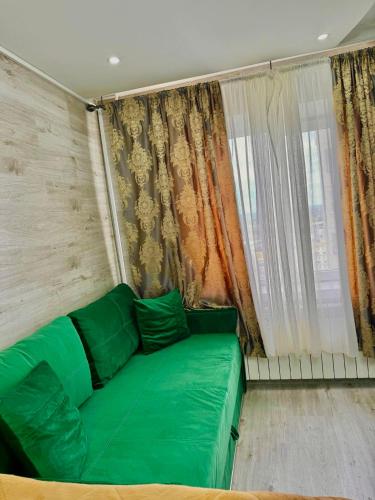 a green couch in a room with a window at Можно оплатить картой in Chişinău