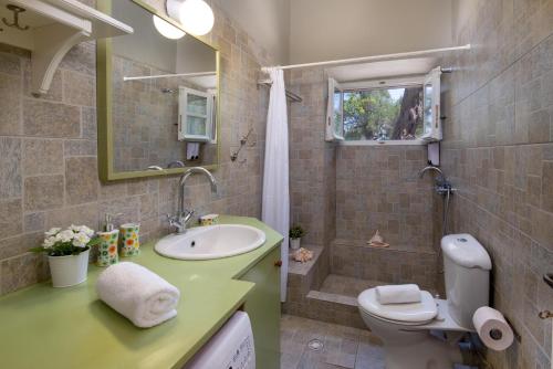 a bathroom with a sink and a toilet and a shower at The Old One by All About Paxos in Kourtaíïka