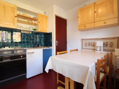 une cuisine avec une table et un chiffon de table blanc dans l'établissement Appartement cosy à Val Cenis Lanslebourg, 300m des pistes, 4/5 personnes, balcon, garage inclus - FR-1-508-62, à Lanslebourg-Mont-Cenis
