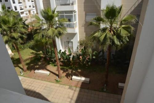 a view of a courtyard with palm trees and a building at Apprt Proche de Technopolis, l'aéroport,et l'UIR in Oulad Yakoub