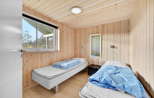 two beds in a room with wooden walls and a window at Holiday Home Kronens Have Tranekær X in Hou