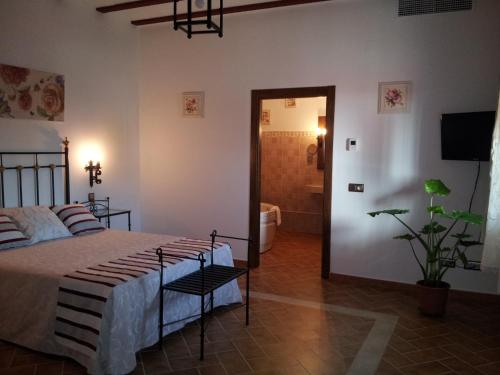 a bedroom with a bed and a room with a bathroom at Casa Rural con jacuzzi y pista de padel - Casa de Pacas in Bolaños de Calatrava