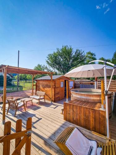 une terrasse en bois avec un bain à remous et un parasol dans l'établissement Maison normande au bord de Seine, Le Verger de Pacôme, à Anneville-Ambourville