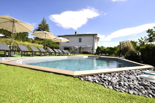 a swimming pool in a yard with chairs and umbrellas at Gan Eden B&B in Monterenzio