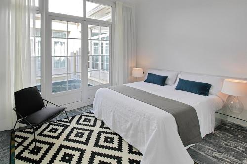 Apartamentos Plaza Constitución - Larios في مالقة: غرفة نوم بيضاء مع سرير كبير ونافذة