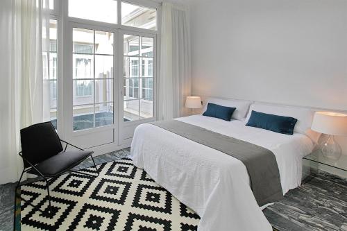 a white bedroom with a large bed and a window at Apartamentos Plaza Constitución - Larios in Málaga