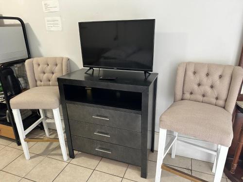 two chairs and a television on a dresser with a tv at Full bed studio near Temple and Center city Philadelphia in Philadelphia