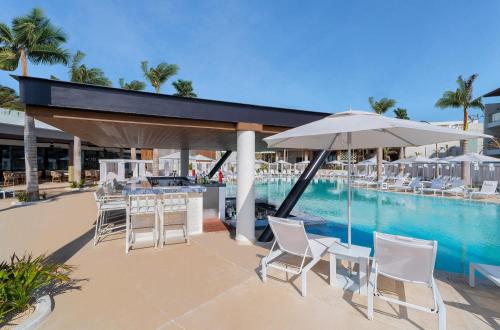 a swimming pool with chairs and an umbrella next to a resort at The Eden by Desire Riviera Maya All Inclusive - Couples Only in Puerto Morelos