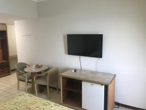 a room with a tv and a table and chairs at Recife Mar Flats Hotel in Recife