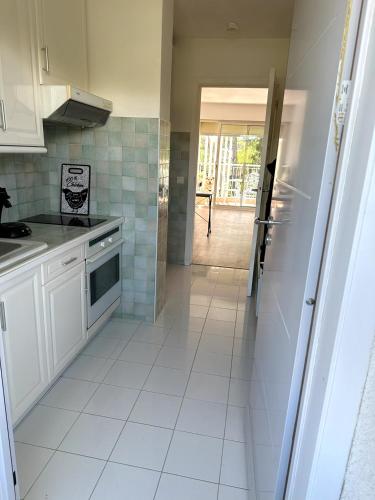 une cuisine avec des armoires blanches et un sol carrelé dans l'établissement le boreal bord de mer avec piscine, à Saint-Raphaël