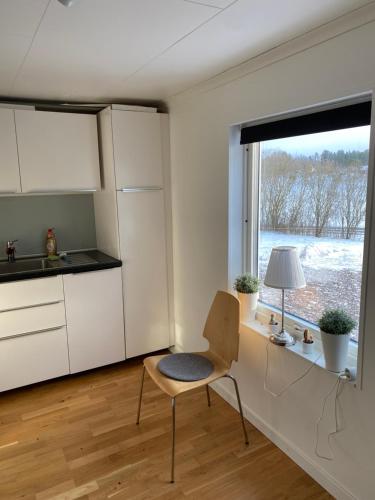 a kitchen with white cabinets and a chair and a window at Mellan Stockbäcken 1 in Nyköping
