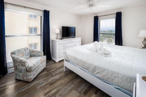 a bedroom with a bed and a chair and a television at Gulfside 503 in Fort Walton Beach