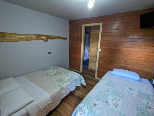 a small bedroom with two beds and a television at Fachwerkhaus zum Hirsch in Oxapampa