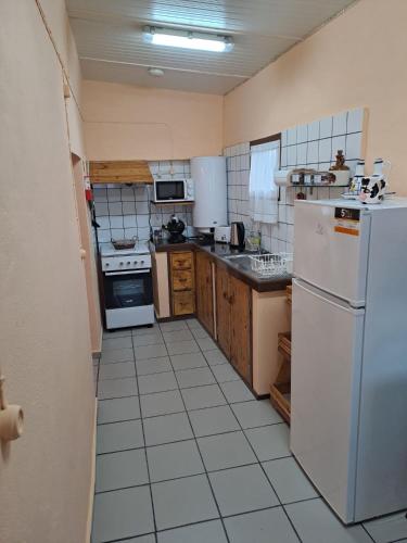 a kitchen with a white refrigerator and a white tile floor at A Casa dos Avós in Lajes das Flores