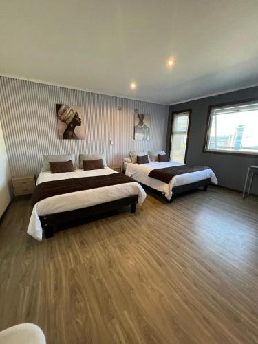 two beds in a large room with wooden floors at Hotel Mackenna in Osorno