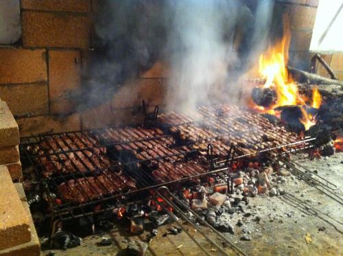 a grill with a lot of meat and flames at Masía La Safranera in Alcoy