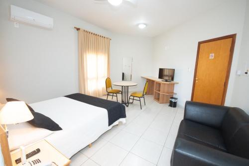 a hotel room with a bed and a couch and a table at Hotel Ouro Lavras in Lavras