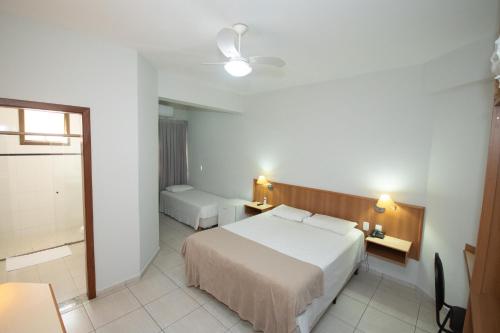 a hotel room with a bed and a bathroom at Hotel Ouro Lavras in Lavras