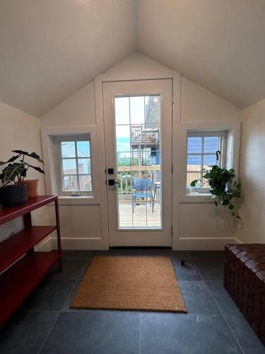 a living room with a door and windows and a table at Heritage-Inspired Guesthouse - Luxe Bath & Elegant Ceilings in Edmonton