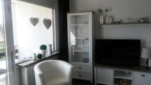 een woonkamer met een witte stoel en een televisie bij Ferienwohnung Steffens Hahnenklee in Hahnenklee-Bockswiese