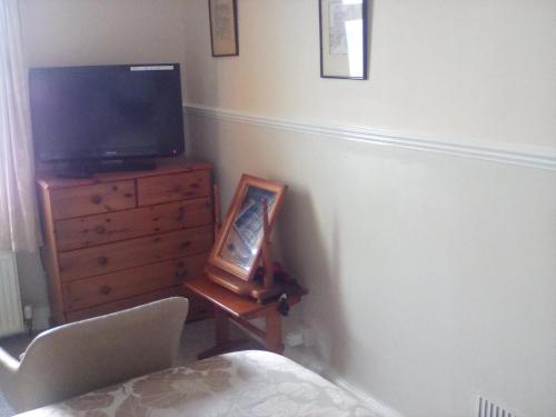 a bedroom with a tv and a dresser with a picture at The Merchants House in Cairnryan