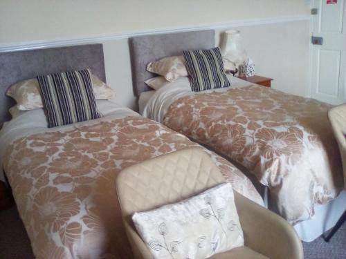 a room with two beds and a chair and a chair at The Merchants House in Cairnryan