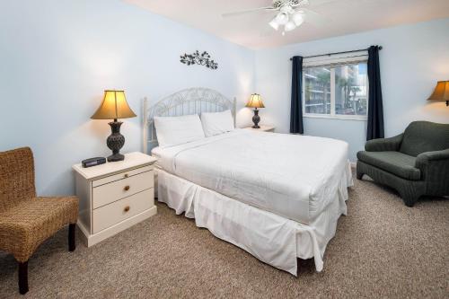 a bedroom with a bed and a chair and a window at Dune Pointe 201 in Fort Walton Beach