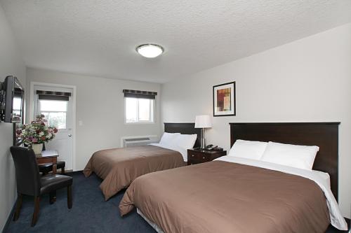 una habitación de hotel con 2 camas y una silla en Travelodge by Wyndham Wetaskiwin, en Wetaskiwin