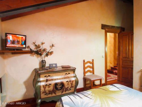 um quarto com uma cama e uma televisão na parede em Hotel Rural Sucuevas em Mestas de Con