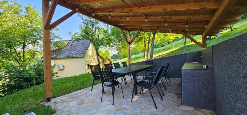 a patio with a table and chairs under a wooden roof at NEO resort Hill jezero Bruje in Erdevik