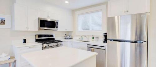 a kitchen with white cabinets and a stainless steel refrigerator at Jenner Inn in Jenner