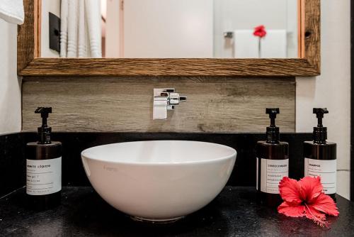 a bathroom sink with three bottles and a white bowl at Triângulo Noronha in Fernando de Noronha
