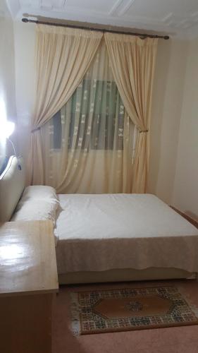 a bedroom with a bed and a window with curtains at Maison d'hôtes afoulki tafraout in Tafraoute