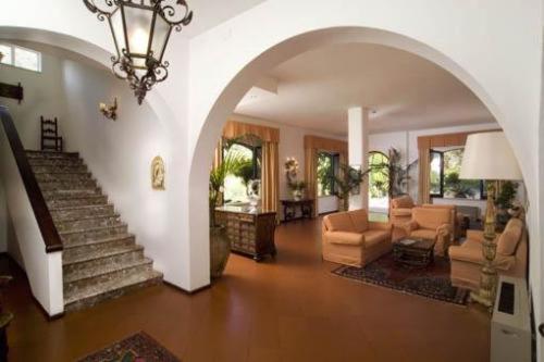 a large living room with a staircase and a living room with chairs at Hotel Villa Sirina in Taormina